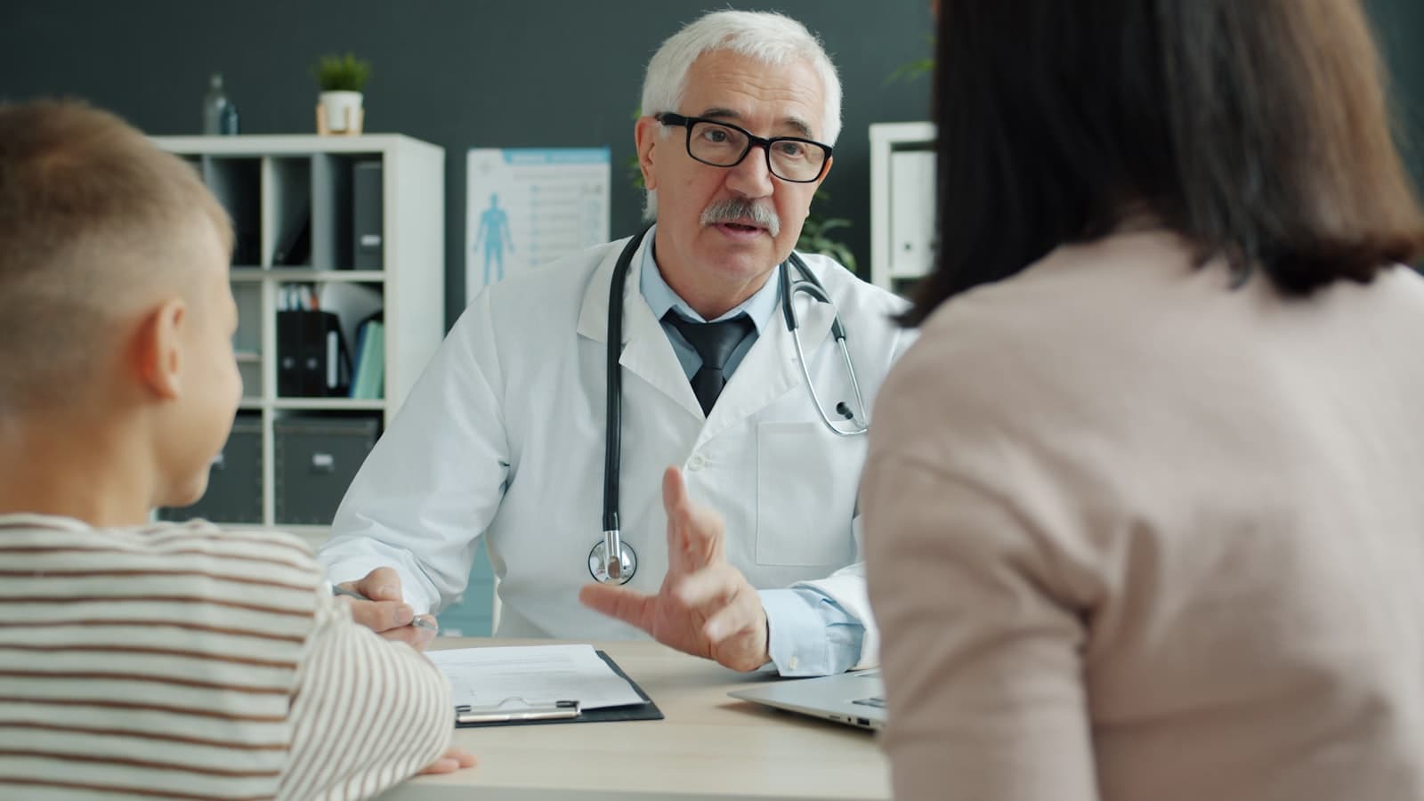 Médico atendendo mãe e filho no consultório
