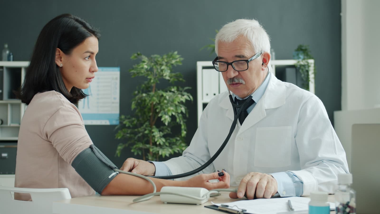 Médico aferindo a pressão arterial de uma paciente